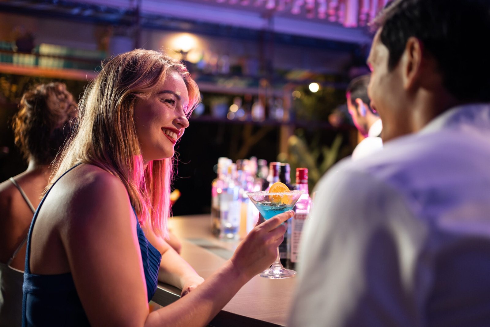 Beautiful young couple having fun, drinking alcohol cocktail in a bar.